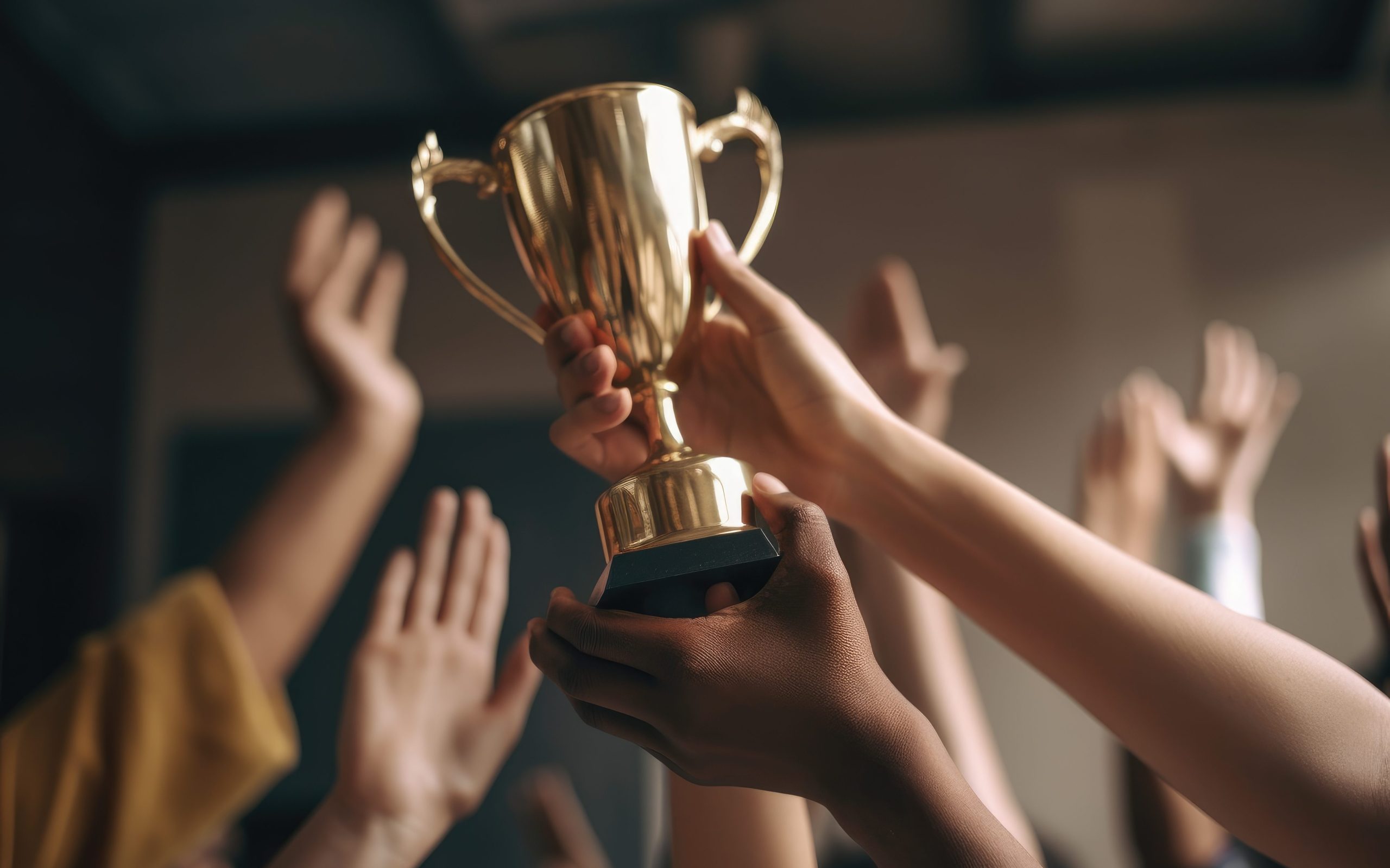 Duas mãos segurando um troféu enquanto alguém comemora depois de ganhar um prêmio